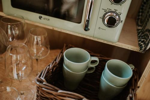 a basket with two cups and wine glasses on a table at Bonita cabaña de los arboles en La Rioja , Durmiendo entre arboles in Anguciana