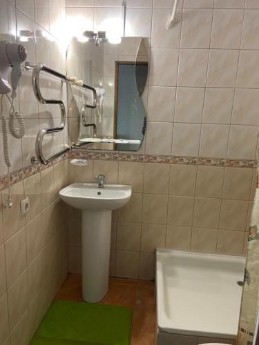 a bathroom with a sink and a mirror and a tub at Золотий Лев in Zvenyhorodka