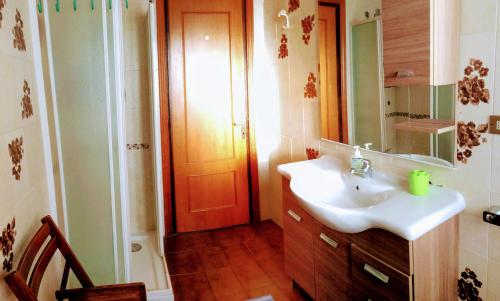 łazienka z umywalką, lustrem i drzwiami w obiekcie Casa Vacanze Sole e Mare w mieście Teulada