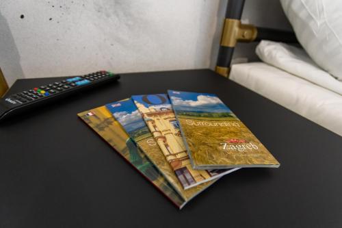 a book on a table next to a remote control at Timeout Heritage Hotel Zagreb in Zagreb