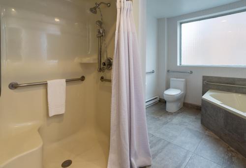 a bathroom with a shower and a tub and a toilet at Crowne Plaza Fredericton Lord Beaverbrook by IHG in Fredericton