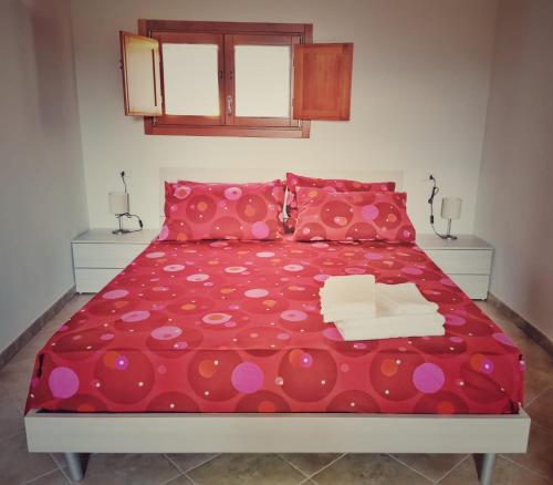 a bedroom with a red bed with red and pink pillows at L’oasi di Cice in Rufina