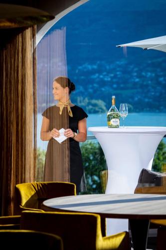 a woman standing at a table with a glass of wine at Hôtel L'Incomparable Aix-Les-Bains in Tresserves