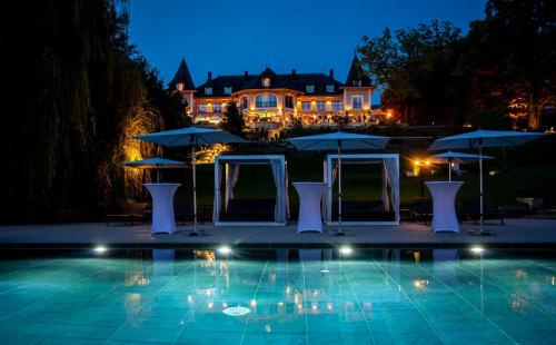 a pool with umbrellas and a house in the background at Hôtel L'Incomparable Aix-Les-Bains in Tresserves