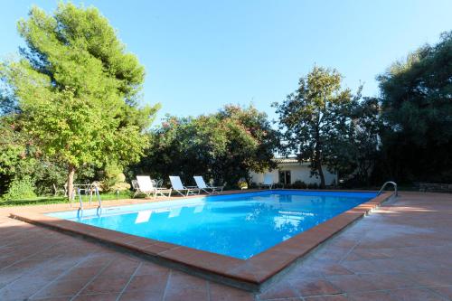 a swimming pool in a yard with chairs and trees at Dattilo in Torre Melissa