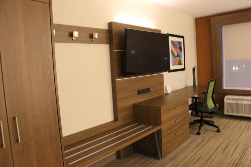 a hotel room with a tv and a desk with a computer at Holiday Inn Express & Suites - Phoenix - Airport North by IHG in Phoenix