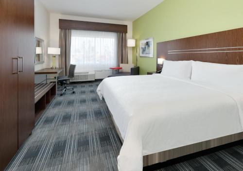 a hotel room with a large bed and a desk at Holiday Inn Express & Suites Dallas NW - Farmers Branch by IHG in Farmers Branch