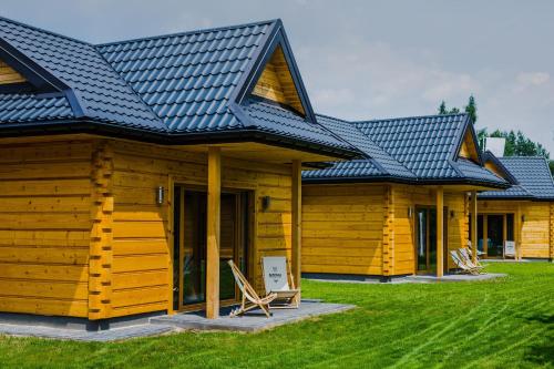 a log cabin with a blue roof and some chairs at Domki Osada Bacówka Radawa & SPA in Radawa