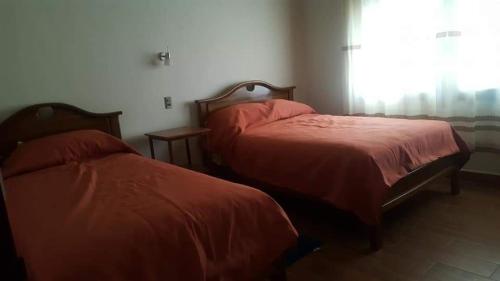 two beds with red sheets in a room with a window at Hotel el super 8 in Santa Cruz de la Sierra