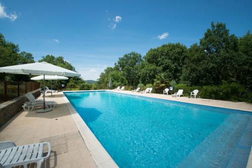 une piscine avec des chaises et un parasol dans l'établissement Domaine de Gayfié, à Salvagnac-Cajarc