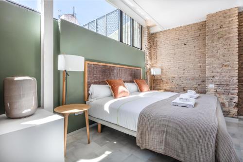 a bedroom with a large bed and a brick wall at Slow Suites Maestranza in Seville