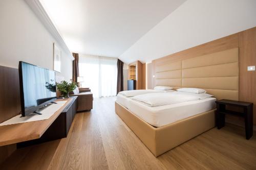 a bedroom with a large bed and a flat screen tv at Hotel Haus am Hang in Caldaro