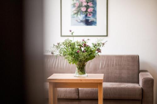 a vase of flowers on a table next to a couch at Hotel Haus am Hang in Caldaro