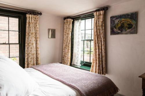 a bedroom with a bed and two windows at The Bull Inn in Totnes