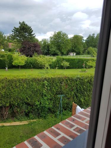 a view of a garden with a brick wall and a field at Chambres d'Hôtes Arques en Ciel in Arques-la-Bataille