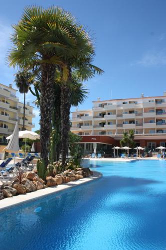 een groot zwembad met palmbomen voor een hotel bij Easy4Stay by Beach Resort in Portimão