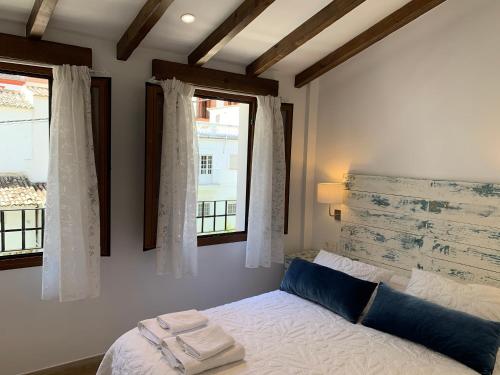 a bedroom with a bed and two windows at Casa Cueva El Puente in Setenil