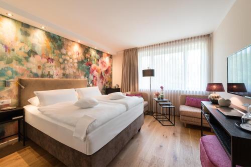 a bedroom with a large bed and a living room at MUNTE - Wellnesshotel am Stadtwald in Bremen