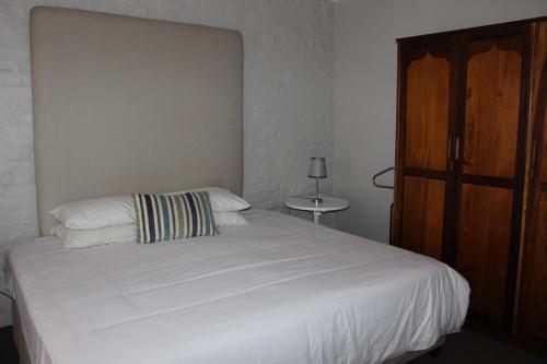 a bedroom with a white bed and a wooden cabinet at Riempie Estate Self-Catering in Oudtshoorn