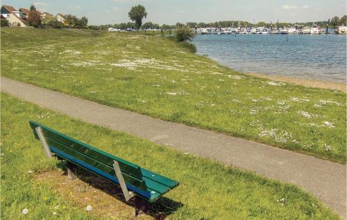 a green park bench next to a path next to a body of water at Porta Isola - Villa Water in Stevensweert