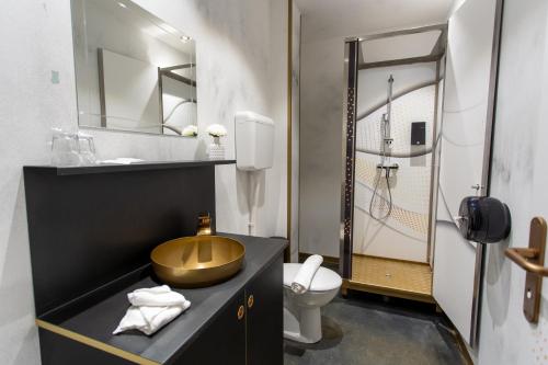 a bathroom with a gold sink and a toilet at Timeout Heritage Hotel Zagreb in Zagreb