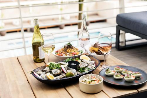 a table with plates of food and glasses of wine at Hotel June West LA, a Member of Design Hotels in Los Angeles
