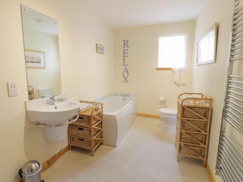 a bathroom with a sink and a tub and a toilet at Lon Cottage in Clunie