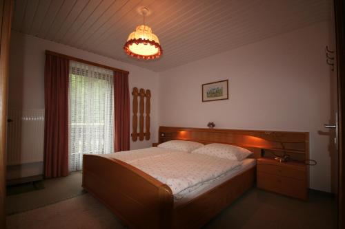 a bedroom with a large bed and a chandelier at Haus Ebner in Sankt Gilgen