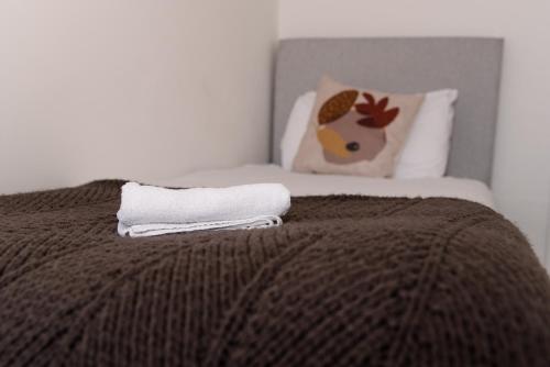 - un lit avec une couverture brune et une serviette blanche dans l'établissement GreenStar Apartments, à Dundee