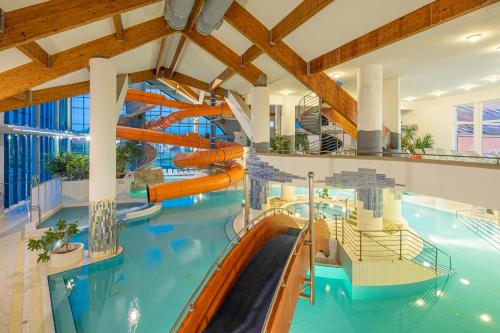 a large indoor swimming pool with a water slide at Kehida Termál Resort & Spa in Kehidakustány
