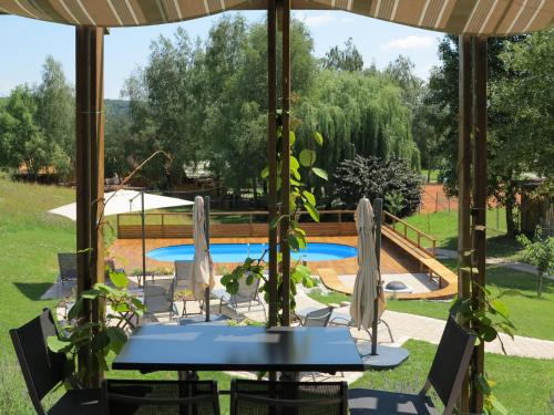 una mesa y sillas bajo una sombrilla junto a una piscina en Naturasort Holiday Houses, en Pesnica pri Mariboru