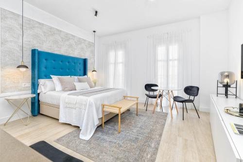 Un dormitorio blanco con una cama azul y una mesa en iloftmalaga Studio Apartments, en Málaga