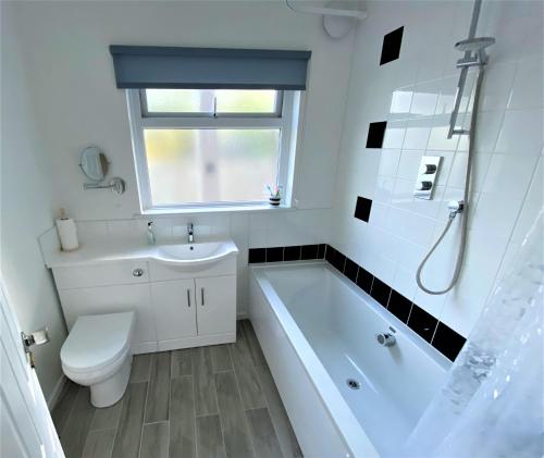 a bathroom with a tub and a toilet and a sink at Luxury Suntrap in Private Complex St Leonards in Hastings