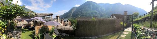a building with a fence with a mountain in the background at B&B Osteria Morganti in Someo