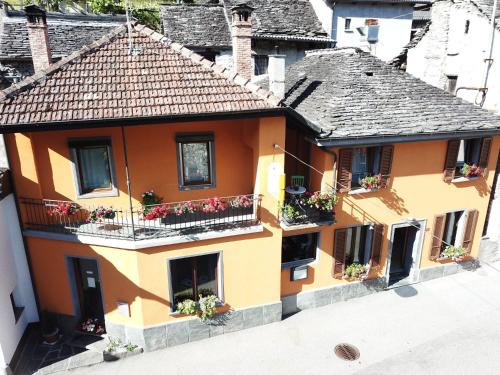 an orange building with flower boxes on its windows at Donjon B&B e Ristorante in Someo