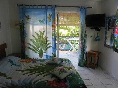 1 dormitorio con 1 cama y puerta corredera de cristal en Résidence des îles, en Le Marin