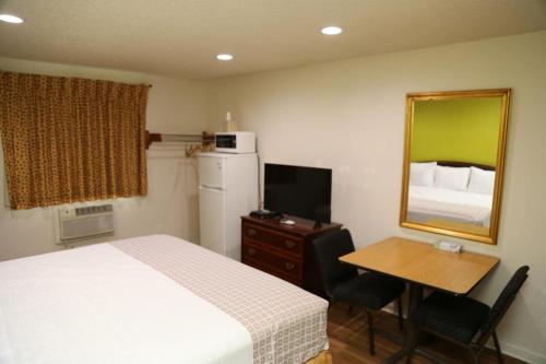a bedroom with a bed and a table and a mirror at Americas Express Inn Rocky Mount in Rocky Mount