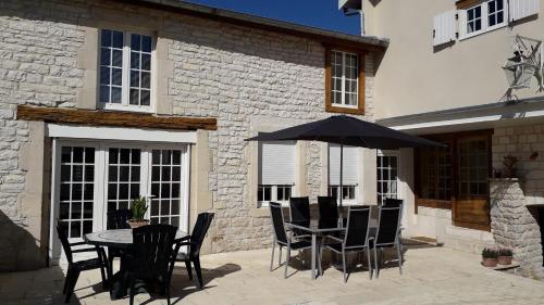 a patio with a table and chairs and an umbrella at Chez Madgi et Jean-Mi in Froncles