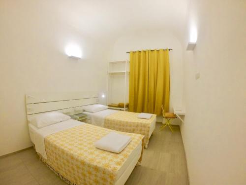 a hotel room with two beds and a yellow curtain at Central Savona in Savona