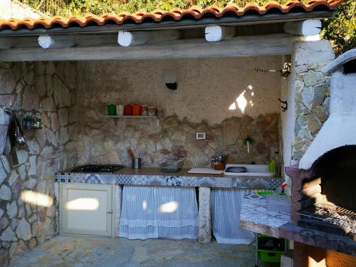 an outdoor kitchen with a stove and a stone wall at Villetta Delizia in Scopello