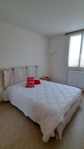 - un grand lit blanc avec un oreiller rouge dans l'établissement GRAND CAP Appartement 2 chambres vue mer, à Saint-Jean-de-Monts