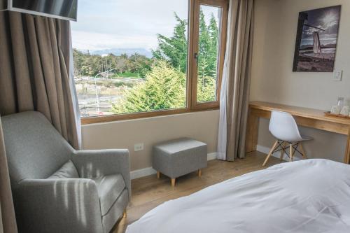 a bedroom with a bed and a chair and a window at Hosteria y Restaurante America in Ushuaia