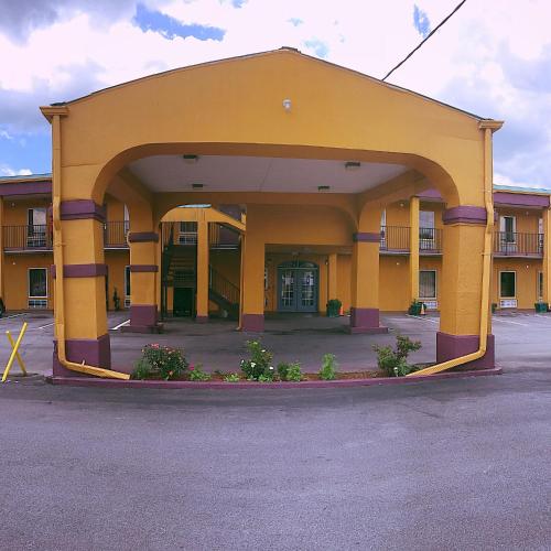 a yellow building with an archway in a parking lot at Travelers Inn Elizabethton in Elizabethton