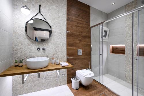 een badkamer met een wastafel, een toilet en een spiegel bij Adell Deluxe Apartments in Kavala