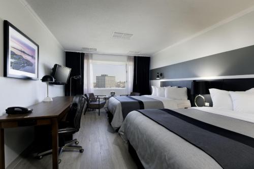 a hotel room with two beds and a desk at Hotel Rimouski in Rimouski