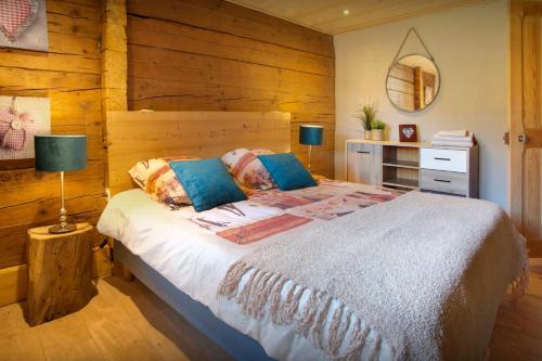 a bedroom with a bed with a wooden wall at Chalet L'Otavalo - OVO Network in Manigod