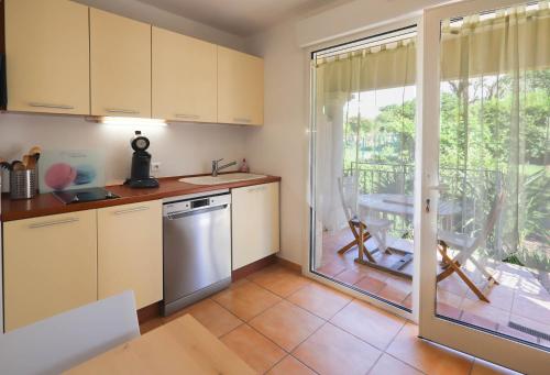 a kitchen with white cabinets and a sliding glass door at Orangeraie du Cap d'Antibes in Antibes