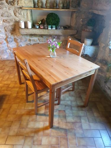 una mesa de madera con 2 sillas y un jarrón de flores. en La Bergerie Crenantine en Crenans