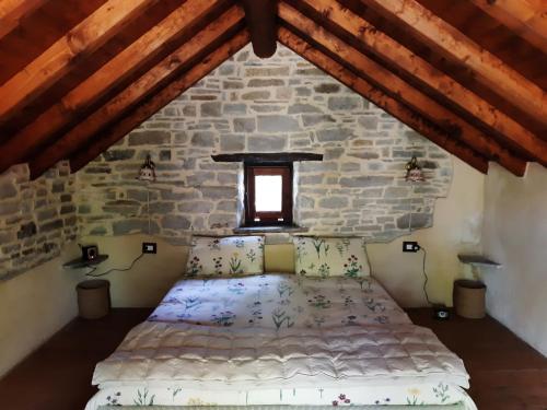 een bed in een kamer met een stenen muur bij Ca' d'Alfieri in Bardi