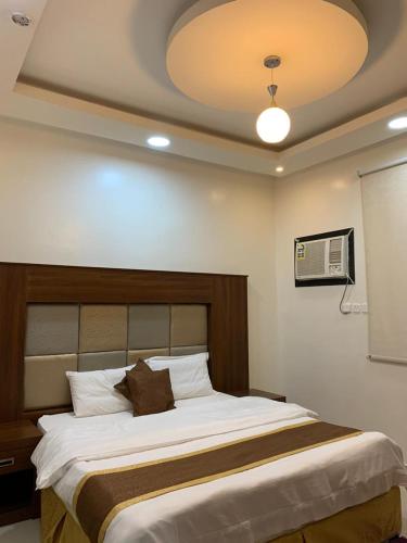 a bedroom with a large white bed with a ceiling at Buyutat Najran Serviced Apartments بيوتات نجران للشقق المخدومة in Najran